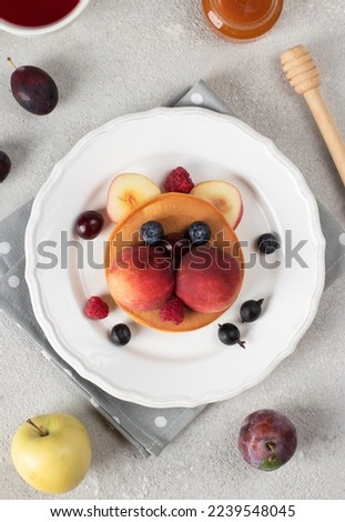 Pancakes with fruits and berries in the shape of cat - funny idea for children's breakfast