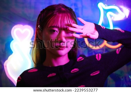 Portrait of a young Asian woman with neon sign Royalty-Free Stock Photo #2239553277