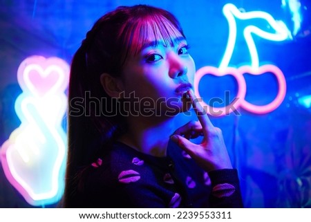 Portrait of a young Asian woman with neon sign