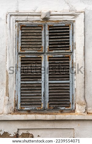 Old window with worn wooden shutters on exterior wall of an old ruined house Royalty-Free Stock Photo #2239554071