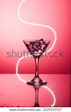 Martini glass with ice. On the bar. Against the background of neon light.