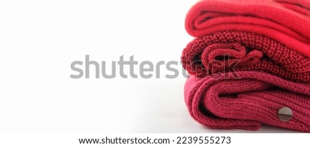 three shades of red and three textures of fabric, woolen knitted sweaters close-up on a white background, copy space
