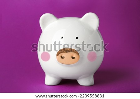 Ceramic piggy bank on purple background. Financial savings