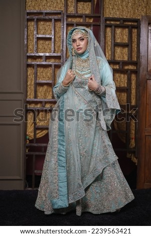 Beautiful Asian hijab girl wearing traditional Bollywood India costume with jewelry set isolated over classic wall design background. Deepavali celebration and Bollywood concept.