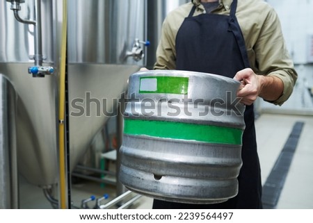 Microbrewery worker carrying heavy keg with beer, small business concept Royalty-Free Stock Photo #2239564497