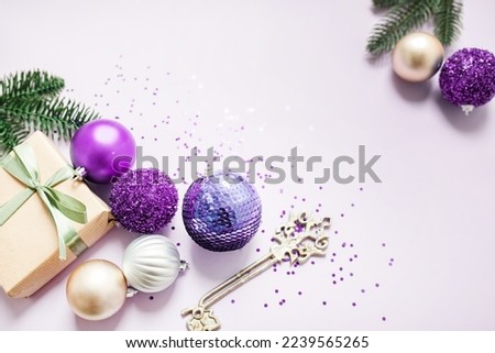 festive New Year's frame layout in purple tones on a lilac background. Christmas decorations, fir branches and glitter. flat lay. top view. copy space