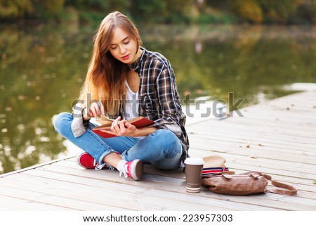 Young beautiful girl sitting on a pier Royalty-Free Stock Photo #223957303