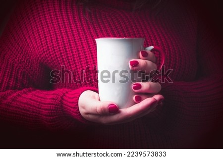 Woman with cozy red sweater holding white mug for mockup.