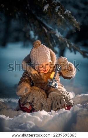Little girl with a lantern glaring in the park on a winter evening