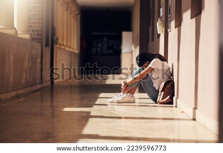 Sad, lonely and girl with depression at school, crying and anxiety after bullying. Mental health, tired and unhappy student in the corridor after problem in class, education fail and social isolation Royalty-Free Stock Photo #2239596773