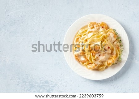 Seafood pasta. Pappardelle with shrimps and cream sauce in a white plate, with fresh thyme shot from above with copy space Royalty-Free Stock Photo #2239603759