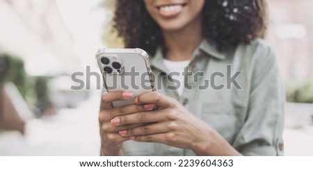 Smiling woman using smartphone outdoors, panoramic banner. Young african american woman using smartphone in a city. Technology, connection, communication, modern lifestyle concepts