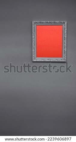 Red background inside wooden frame, gray wall texture