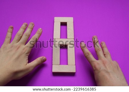 number eight written with wood blocks on purple background and number 8 indicated by finger. number representation in sign language