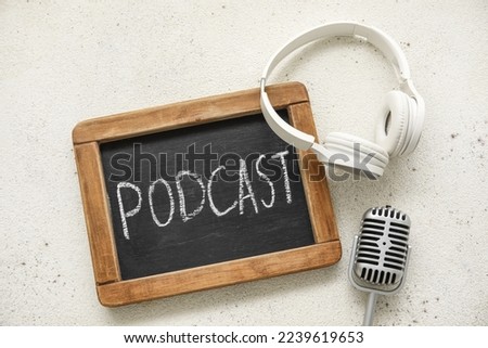Chalkboard with word PODCAST, headphones and microphone on white background