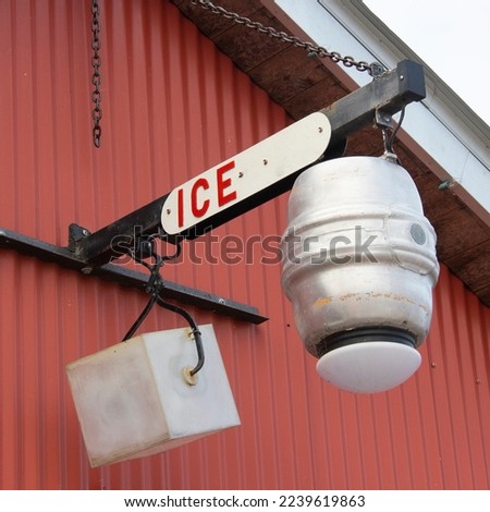 Old sign of a barrel and an ice block with grips hanging outside a red corrugated building in Apalachicola Florida 