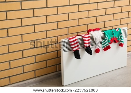 Baby elf costume drying on electric radiator near brick wall