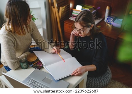 two women young caucasian female student sitting at home with her mentor teacher looking to the notebook explaining lesson study preparing for exam learning education concept real people copy space Royalty-Free Stock Photo #2239622687