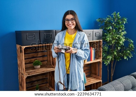 Young hispanic woman smiling confident usint vintage camera at home