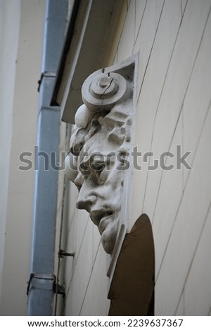 a fragment of the facade of a historical building with a sculptural accent of a human face