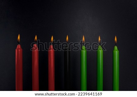 Kwanzaa holiday background. Seven candle light on black background. Afro American holiday concept. Copy space.