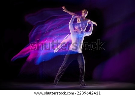 Support. Portrait of young man and woman, figure skating athletes dancing isolated over black background in neon with mixed lights. Concept of movement, sport, beauty, competition, dance, choreography