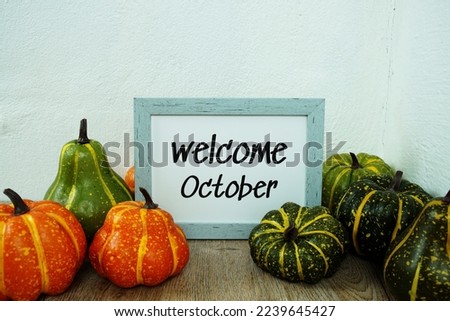 Welcome October typography text with pumpkin decoration on wooden table