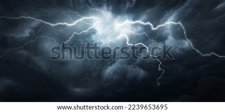 Thunderous dark sky with black clouds and flashing lightning. Panoramic view. Concept on the theme of weather, natural disasters, storms, typhoons, tornadoes, thunderstorms, lightning, lightning. Royalty-Free Stock Photo #2239653695