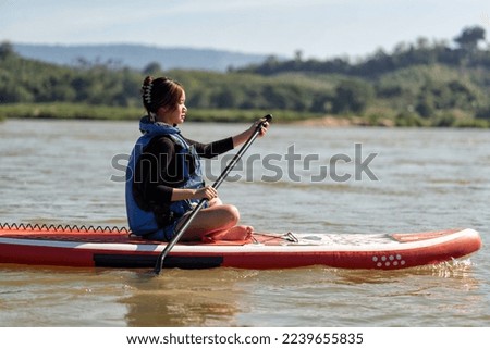 Beautiful girl on holiday activity paddling on a sup boards on a large river on summer day