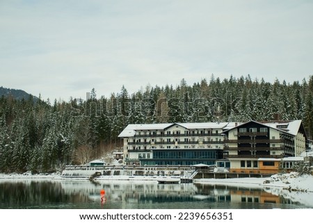 lakeside hotel inn in frozen forest in european alps in winter in december
