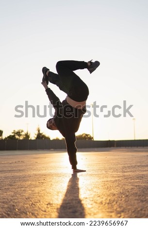 Guy doing parkour and breakdancing tricks at sunset in the street Royalty-Free Stock Photo #2239656967