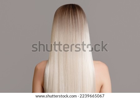 Portrait of a beautiful young blonde woman with long spicy hair. Back view