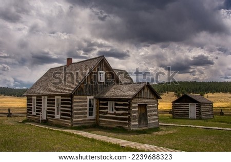 Old historic log cabins stand in a Colorado high country meadow beneath the stormy skies of a late summer day. Royalty-Free Stock Photo #2239688323