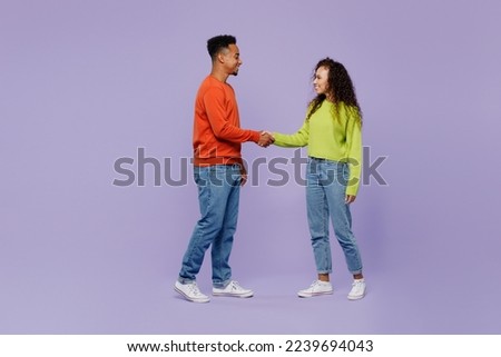 Full body young couple friends family man woman of African American ethnicity wear casual clothes together hold hands folded handshake gesture isolated on plain purple background Friendship concept Royalty-Free Stock Photo #2239694043