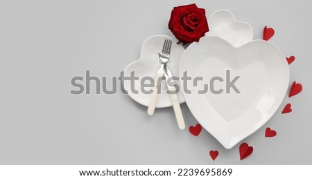 Table setting for Valentine's Day with red hearts and rose flower on grey background with space for text