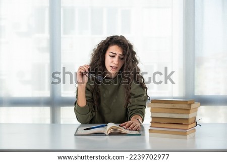 Young college woman law student frustrated with pile of books she need to read and study for exam. Future lawyer girl feeling anxious and nervous before exam. Education concept Royalty-Free Stock Photo #2239702977