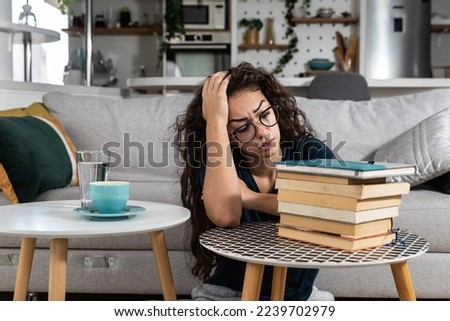 Young college woman law student frustrated with pile of books she need to read and study for exam. Future lawyer girl feeling anxious and nervous before exam. Education concept Royalty-Free Stock Photo #2239702979