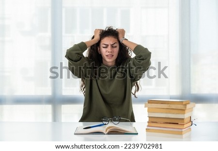 Young college woman law student frustrated with pile of books she need to read and study for exam. Future lawyer girl feeling anxious and nervous before exam. Education concept Royalty-Free Stock Photo #2239702981