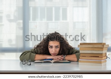 Young college woman law student frustrated with pile of books she need to read and study for exam. Future lawyer girl feeling anxious and nervous before exam. Education concept Royalty-Free Stock Photo #2239702985