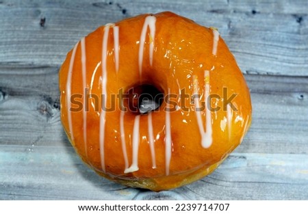 Mango flavored ring donut with white chocolate sauce, A glazed, yeast raised, American style ring doughnut, type of food made from leavened deep fried dough sweet snack, selective focus and isolated