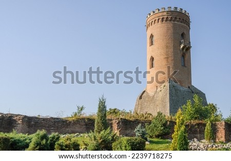 Medieval old brick tower of castle. Medieval building. Tower of ancient castle with opened windows. Historic architectural element on blue sky background.