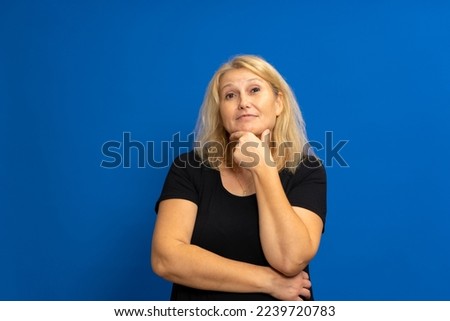 Closeup photo of amazing lady looking up into empty space, thinking deeply, creative person, arm on chin, black casual clothes, isolated blue color background.