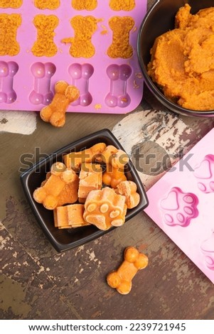 Pumpkin dog treats in bone and paw print shapes.  Royalty-Free Stock Photo #2239721945