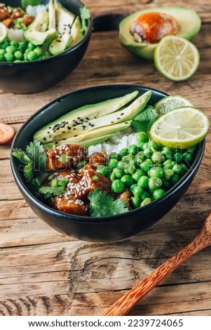 Buddha bowl with crispy sesame chicken asian style. Sweet and sour fried chicken with steamed rice, peas and acocado Royalty-Free Stock Photo #2239724065