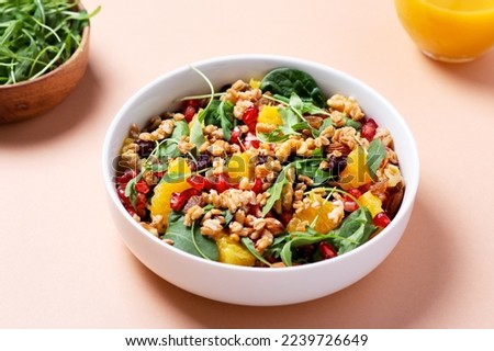 Healthy salad with spelt, oranges, pomegranate seeds. greens and nuts on light background, minimal style, top view, copy space Royalty-Free Stock Photo #2239726649