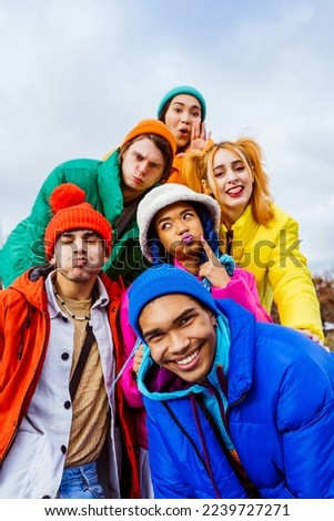 Multiracial group of young happy friends meeting outdoors in winter, wearing winter jackets and having fun - Multiethnic millennials bonding in a urban area, concepts about youth and lifestyle Royalty-Free Stock Photo #2239727271