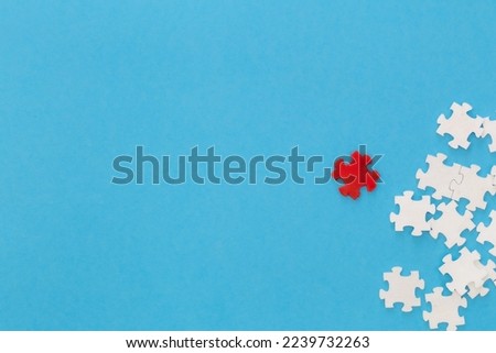 White puzzles and one red on a blue background, flat lay.