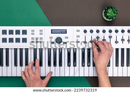 Hands of a man playing musical keys on a colored background, flat lay.