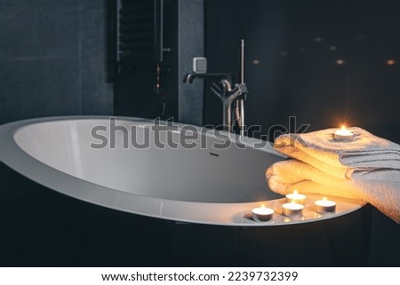 Bathroom interior with towels and candles at night.