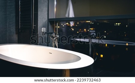 Interior of a modern bathroom with a window overlooking the city.
